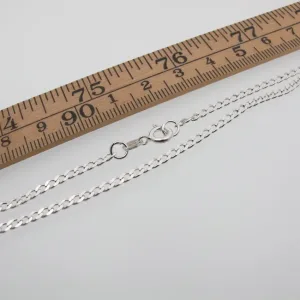 Pansarkedja 2,6mm Halskedja 50-70cm silverhalsband med karbinlås visas bredvid en trälinjal i tum, som visar dess längd.