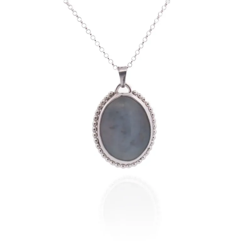 Halsband med handslipad Kalcedon 38x25mm är ett silverhalsband med ett ovalt, handskuret gråblått kalcedonhänge kantat av pärlor, mot en vit bakgrund med en subtil reflektion.
