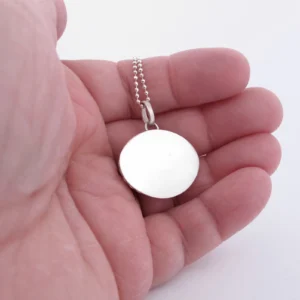 Närbild av en hand som håller i Halsband med handslipad Kalcedon 32x23mm på en pärlkedja, mot en vit bakgrund.