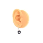 Örhänge Krona med porslin - Adam visas på en naturtrogen, köttfärgad modellöronmodell med en rund, mörkblå porslinssten infattad i silver mot en slät vit bakgrund.