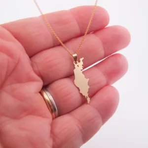 En hand visar Hängsmycke i 14K Guld Gotland, ett guldhalsband med ett hänge format som Gotland. Personen bär en guld- och silverring på ringfingret.