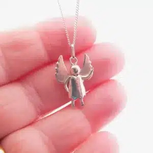En hand håller i Handgjord Silverängel 25mm, ett änglahänge i silver med utsträckta vingar och runt huvud, fäst vid ett delikat kedjehalsband mot en enkel, ljus bakgrund.