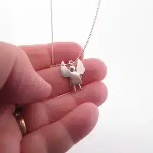 En hand visar Handgjord Silverängel 25mm, ett delikat silverhalsband med ett ängelhänge med utsträckta vingar, mot en vit bakgrund.