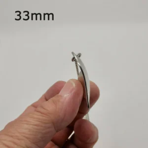 En hand håller i en Handgjort Silverhjärta 33x27mm, sedd från sidan bredvid en liten skruv. "33mm" visas i övre vänstra hörnet för att indikera storlek. Bakgrunden är enfärgad vit.