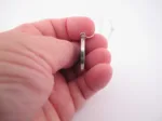En hand håller Porslinssmycke - Gustavsberg 24mm, ett elegant runt silverörhänge, mot en vit bakgrund.