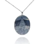 Porslinssmycke - Gustavsberg: Ovalt hängande halsband med en blåvit bild av ett slott med tak och träd, fäst på en tunn silverkedja.