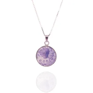 Porslinssmycke - Lila Fasan är ett delikat silverhalsband med ett runt hänge dekorerat med ett lila blommönster, som visas på en vit bakgrund med en mild reflektion under.