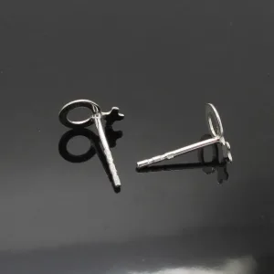 Två små silverörhängen formade som kvinnosymbolen Örhänge med stift - Kvinnosymbol, visas på en blank svart yta - det ena liggande och det andra stående, med sina runda toppar och detaljerade stjälkar.