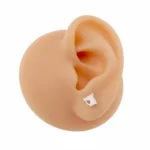 En realistisk silikonmodell av ett mänskligt öra visar "Örhänge med stift - Häst", ett litet silverfärgat hästformat örhänge, mot en vit bakgrund.