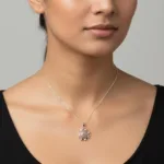 En kvinna bär en svart topp och halsbandet "Halsband med handslipad Hoburgsmarmor 32x23mm", som består av en tunn silverkedja och ett handpolerat stenhänge. Fokus ligger på hennes hals och smyckena mot en neutral bakgrund.