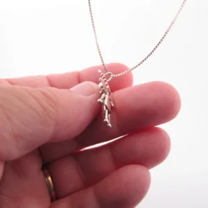 En hand håller i Handgjord Silverängel 26mm, ett handgjort silverhalsband med änglaliknande hänge, mot en vit bakgrund.