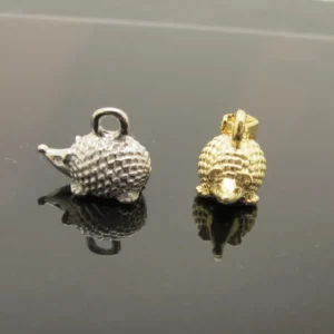 Två Silverberlock Igelkott 14mm igelkottsformade berlocker vilar på en reflekterande svart yta: den ena är silver med en ögla på baksidan och den andra är guld med ett fäste på toppen.