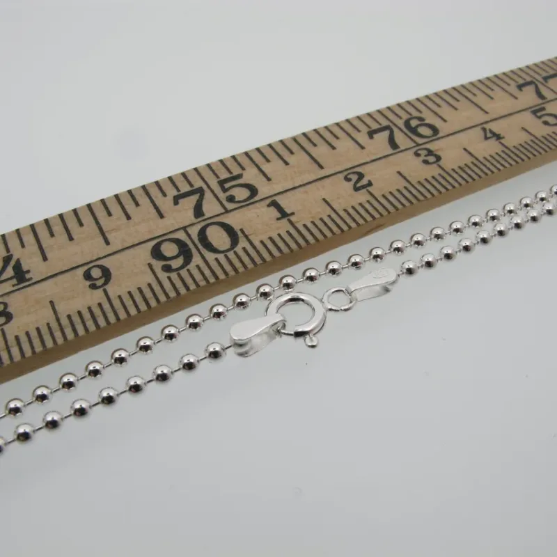 Kulkedja 2mm Halskedja 50-60cm silverkulhalsband med karbinlås visas bredvid en trälinjal märkt i centimeter och millimeter, vilket illustrerar dess ungefärliga längd på 50-60cm.