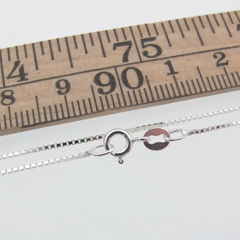 Veneziakedja 0,8mm Halskedja 42-45cm visas bredvid en trälinjal märkt i centimeter och millimeter, vilket ger en tydlig skala för storleksreferens.