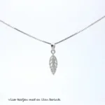 En fin Veneziakedja 0,8mm halskedja (42-45cm) med ett litet bladformat hänge visas mot en enfärgad vit bakgrund. Svensk text längst ned lyder, visar kedjan med en liten berlock.