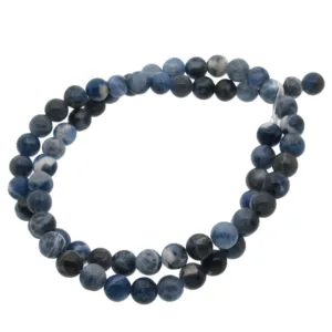 En löst slingrad tråd av Sodalit rund ädelsten 4-6 mm pärlor, med runda polerade blå och mörkblå ädelstenar, visas mot en vit bakgrund.