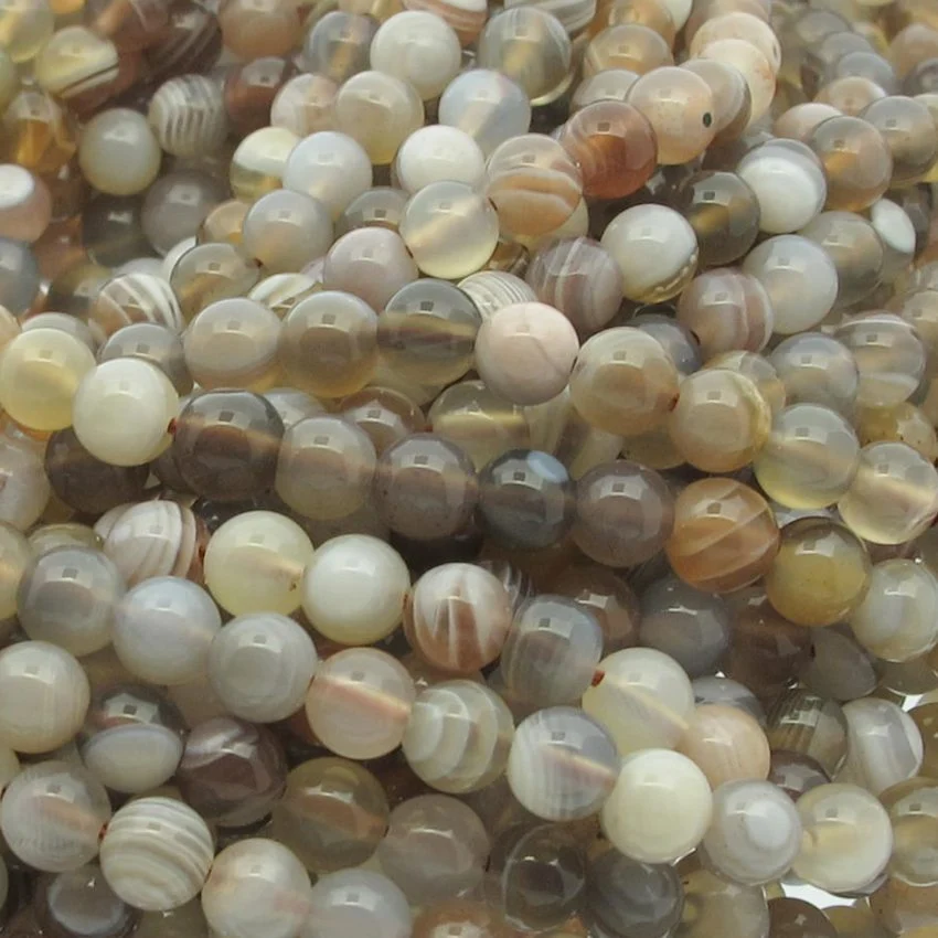 Botswana agat 8mm rund ädelsten 2 Närbild på Karneol rund ädelsten enfärg 4-6 mm pärlor i polerade neutrala toner - brunt, grått, grädde och beige - varav vissa har band- eller randmönster.