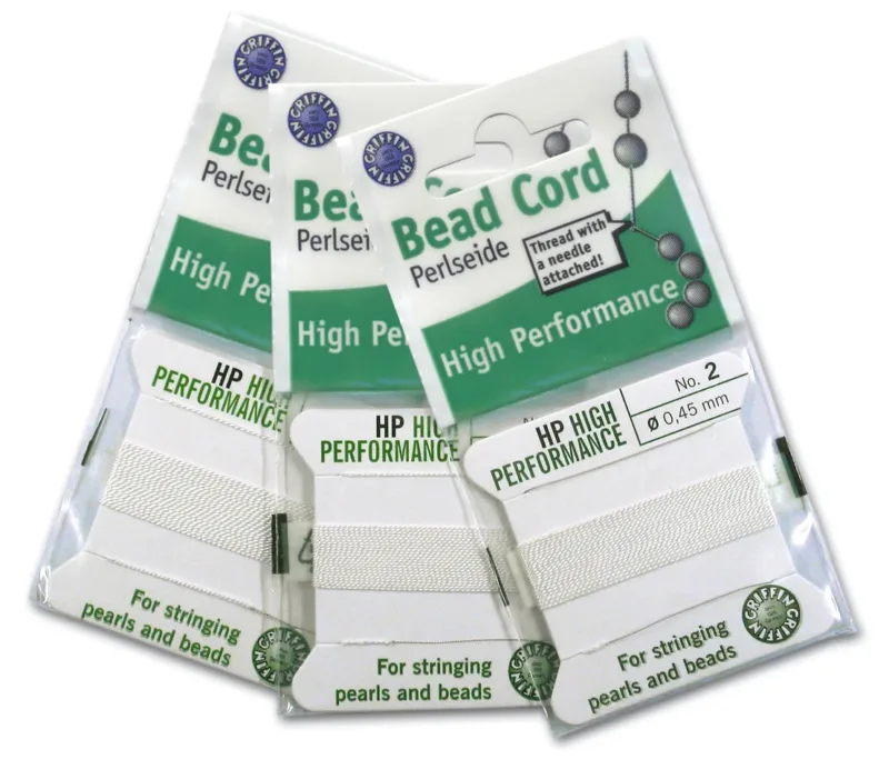 Tre förpackningar Griffin Bead Cord i vit färg, märkta High Performance och No. 2, 0,45 mm, används för att trä pärlor och pärlor. Varje förpackning innehåller tråd med en nål på.
