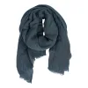 En löst rullad, mörkblå scarf i lättviktstyg med fransiga kanter, mot en vit bakgrund.