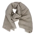 En ljusbrun, löst vävd scarf med fransiga kanter, arrangerad i spiralform mot en vit bakgrund.