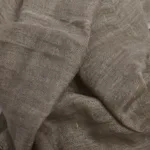 En närbild av Scarf i Linne & Viskos visar löst vävt, skrynkligt beige tyg med synlig struktur och naturliga veck.