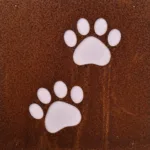 På den rostbruna metallplåten Hund dekorplåt för armeringsnät (14x14 cm) finns två vita tassavtryck, sannolikt av en hund.