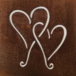 The Hund dekorplåt för armeringsnät 14x14cm är en rostfärgad metallpanel med tre stiliserade hjärtformade utskärningar som släpper igenom ljus och framhäver kontrasten mellan panelen och dess bakgrund.