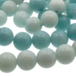 Närbild av Amazonit rund ädelsten 6mm pärlor i ljusblått och vitt med blank, polerad yta. De runda pärlorna är uppträdda med ett synligt blått snöre och arrangerade i ett lätt överlappande mönster.