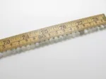 En Månsten rund ädelsten 6mm pärlsträng - en rad med små, runda, ljusa pärlor - mäts med en trälinjal som är märkt i tum och centimeter.