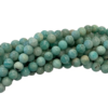 Blue-green, round gemstone beads piled in a corner on a white background, glossy and marbled in color.