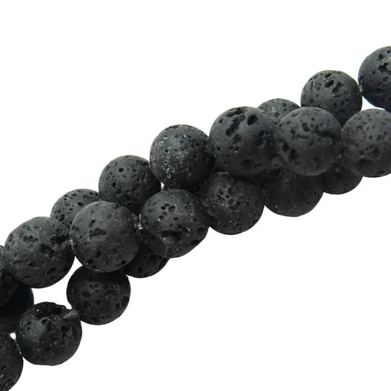 Närbild på Lavasten svarta runda 4-8 mm vaxade pärlor med runda, svarta, vaxade lavastenar med porös textur, diagonalt placerade mot en vit bakgrund.