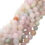 Närbild av flera trådar med Karneol rund ädelsten enfärg 4-6 mm pärlor i mjuka pastellfärger - rosa, ljusgrön, ljusblå, vit - och en orange pärla som sticker ut, alla tätt ihop.