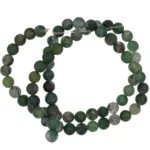 En lös spiral av Mossagat runda ädelstenspärlor (4-8mm), runda och halvgenomskinligt gröna, mot en vit bakgrund.