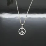 Ett silverhalsband med ett hänge med en fredssymbol som visas på en blank svart yta med en tydlig reflektion av kedjan och berlocken.