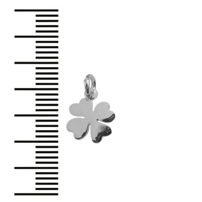 En liten, glänsande fyrklöverberlock med en ögla för fastsättning, placerad bredvid en svartvit måttskala för storleksreferens.