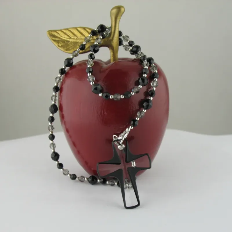 Ett glänsande rött äpple med ett guldblad sitter på en vit yta. En tråd av Silverpärlor runda blanka 2mm/0,9mm pärlor är draperad runt äpplet.