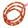 En slingrad tråd av Karneol rund ädelsten 4-6mm, med runda orange och röda genomskinliga pärlor trädda på en synlig röd tråd.