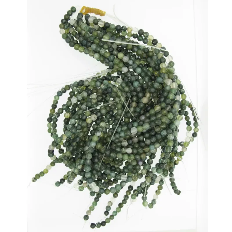 Flera trådar av Mossagat rund ädelsten 4-8mm gröna pärlor är löst sammanlindade mot en vit bakgrund, med några lösa trådar synliga i ändarna.