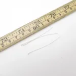 Tre Hattpinne med kula 50mm/0,5mm är placerade bredvid en trälinjal med centimeter- och millimetermarkeringar på en vit bakgrund.