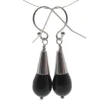 Ett par örhängen tillverkade med Hattpinne med kula 50mm/0,5mm, med svarta droppformade pärlor med silverfärgade lock och krokar, mot en vit bakgrund.