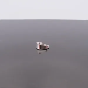 A Trekantsögla slät i sterlingsilver, ett litet, kilformat föremål i sterlingsilver, är centrerat på en reflekterande mörk yta med en vanlig ljus bakgrund.