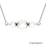 Ett silverkedjehalsband med tre vita Pärlhatt Sterlingsilver 6mm pärlor i mitten, accentuerat av små silverdetaljer. "Inspiration!" visas i det nedre högra hörnet.