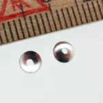 Två 4 mm pärlhattar av sterlingsilver från Pärlhatt med centrala hål är placerade på en vit yta bredvid en trälinjal markerad med röda och svarta måttlinjer.