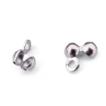 Två små, blanka Knutgömma i Rostfritt stål 6x4mm smyckesfynd med två rundade ändar och en ögla visas mot en vit bakgrund. De är clamshell pärlspetsar för avslutning av smyckestrådar.