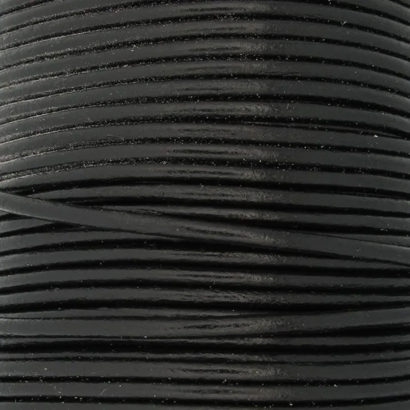 Närbild av flera tätt lindade spolar av svart lädersnöre, staplade horisontellt och fyllande ramen. Texturen verkar slät med en lätt glans.