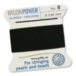 En rulle Smycketråd Griffin Nylon Power Svart, 0,80 mm, extra stark och utan stretch, perfekt för att trä pärlor och kulor. Den svarta nylontråden är prydligt lindad på ett vitt kort.