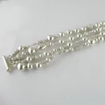 Silverpärlor runda blanka 4mm/1,2mm armbandet har flera strängar av glänsande runda silverpärlor i olika storlekar och texturer, säkrade med ett bar och toggle lås, visat på en vit bakgrund.