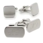 Fyra Manschettknapp i Rostfritt stål visas: två har en slät yta, medan de andra två har ingraverade initialer H F på en rektangulär yta.