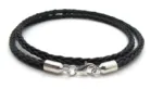 Ett svart flätat läderhalsband med Cylinderformat avslut för rem 5mm silverändar och ett kroklås, snyggt upprullat mot en vit bakgrund.