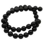 En tråd av glänsande svarta pärlor är lindad i en lös spiral mot en vit bakgrund.